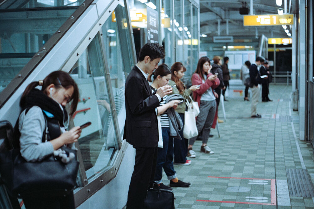 People standing on tran station with phones