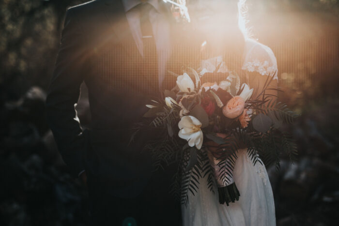 Bridal couple holding flowers in the sun