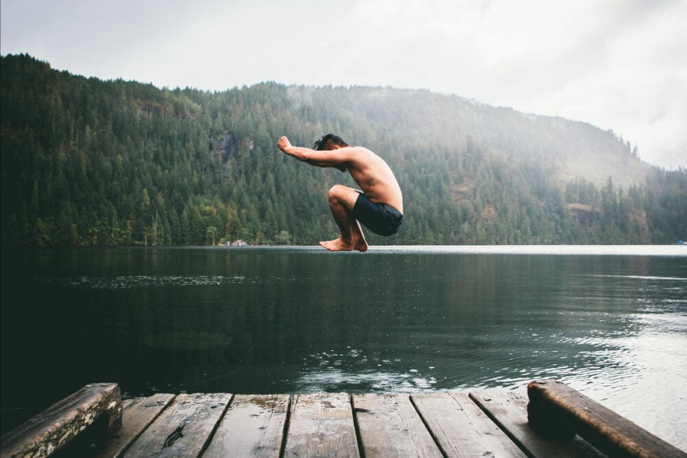 Man jumping into lake from deck
